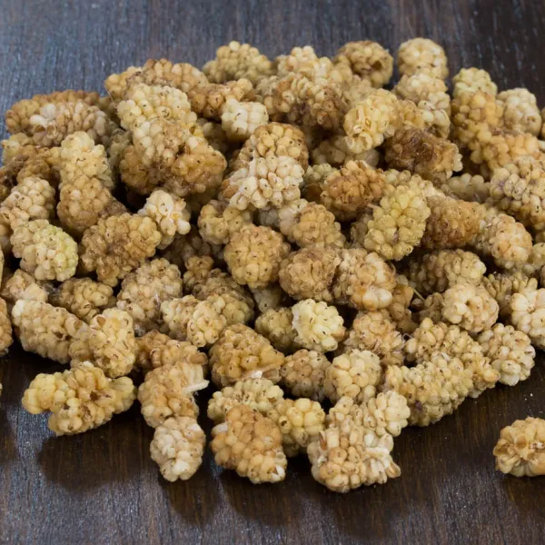 Pale golden dried white mulberries on a wooden table