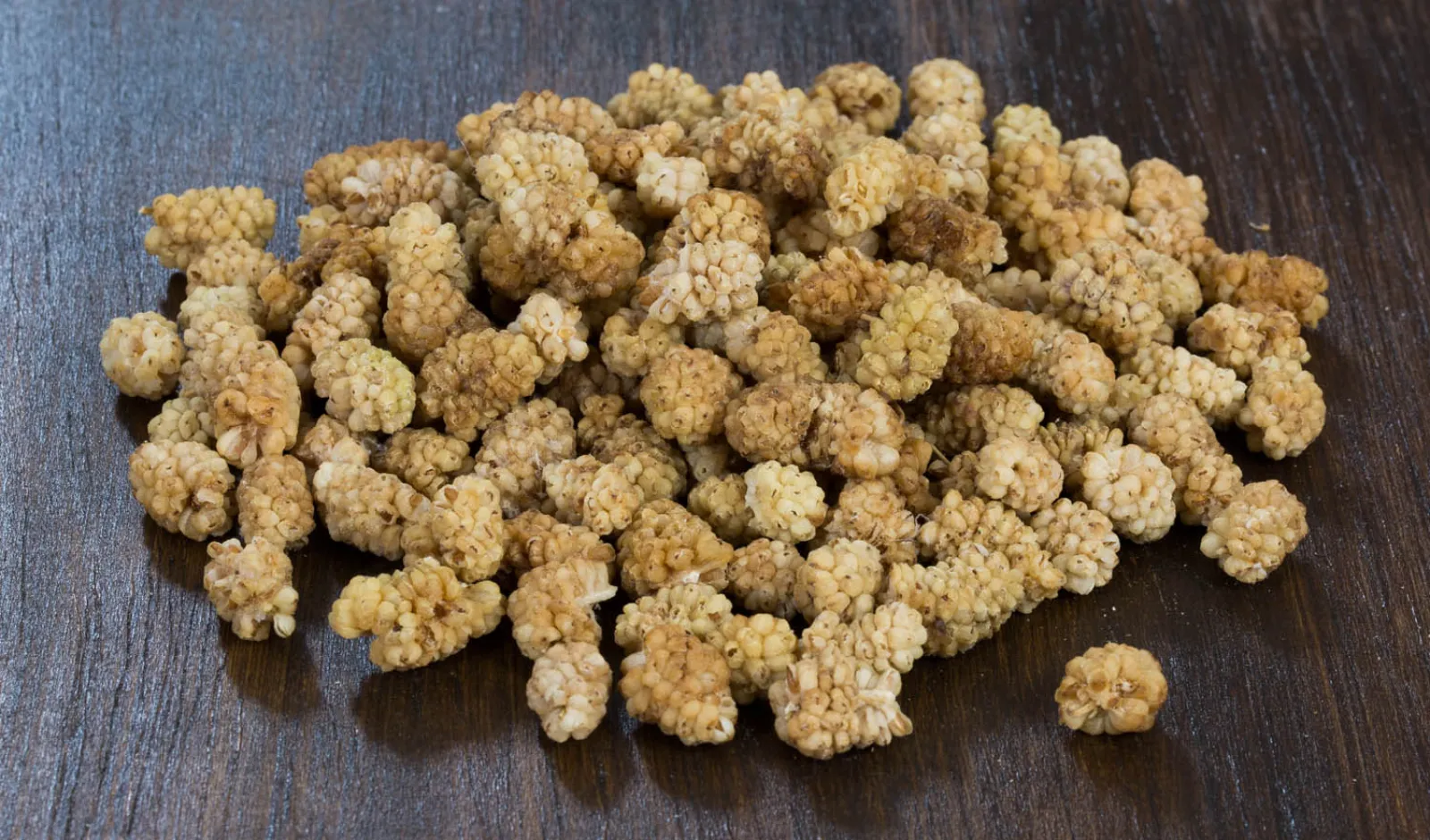 Pale golden dried white mulberries on a wooden table