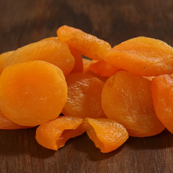 Bright orange dried apricots on a dark wooden surface